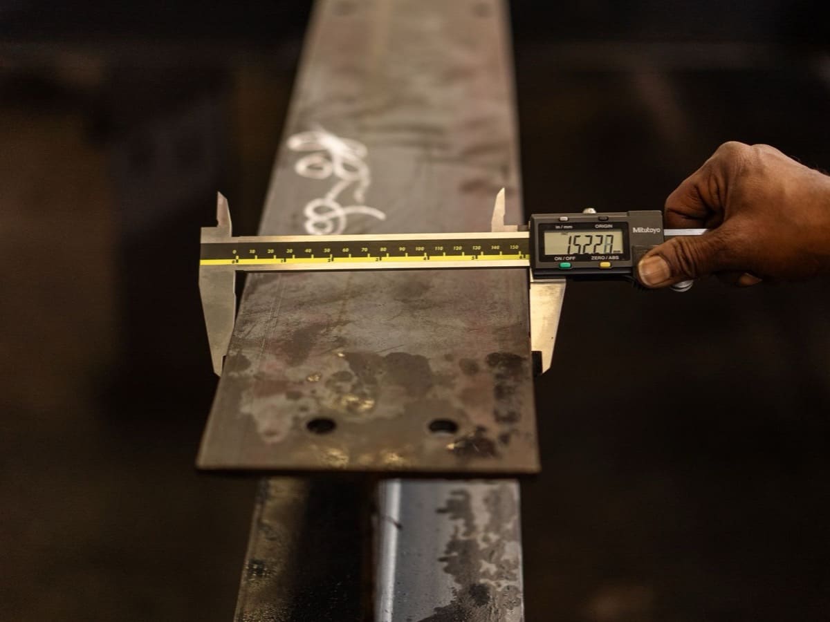 Operatore che misura un profilo metallico con calibro digitale